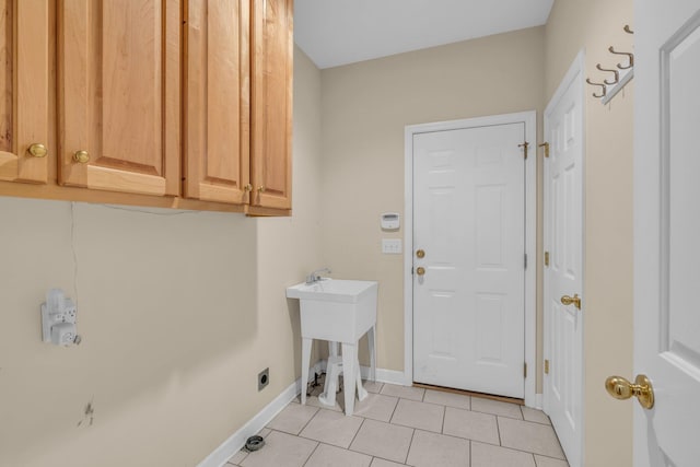 laundry room with electric dryer hookup, light tile patterned floors, cabinet space, and baseboards