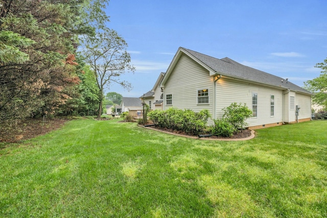view of side of property featuring a lawn, a shingled roof, and crawl space