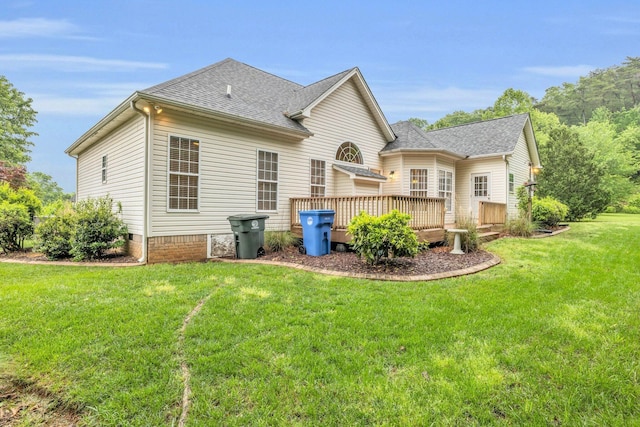 rear view of property with a lawn, a wooden deck, and roof with shingles