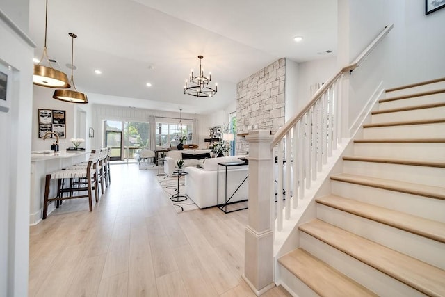 stairway with an inviting chandelier, recessed lighting, wood finished floors, and visible vents