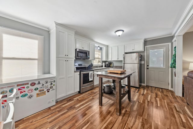 102 Lakeside Dr, Columbia, TN 38401 - kitchen with appliances with stainless steel finishes, wood finished floors, a sink, white cabinets, and ornamental molding