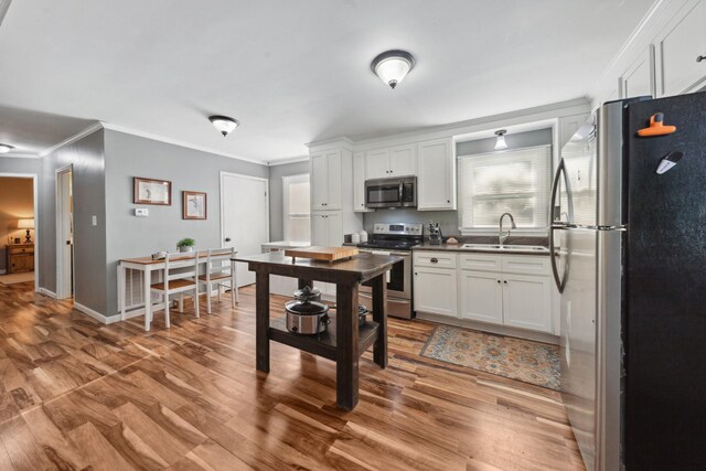 102 Lakeside Dr, Columbia, TN 38401 - kitchen featuring crown molding, wood finished floors, a sink, stainless steel appliances, and white cabinetry