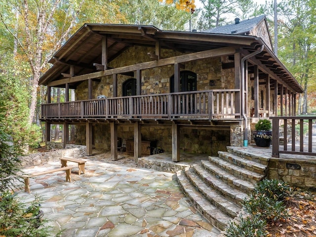 view of front of property featuring a patio, a wooden deck, stone siding, and stairs
