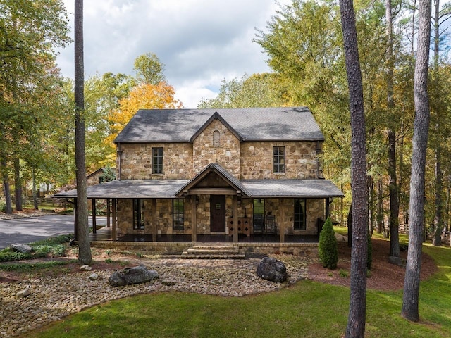 view of front of property featuring a porch, a front lawn, and stone siding