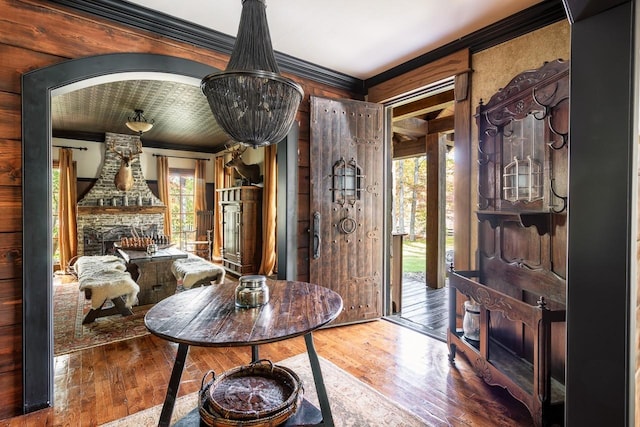 dining room with ornamental molding, a stone fireplace, and wood-type flooring