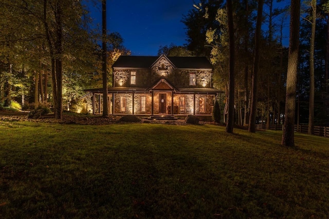 view of front of home featuring a porch, a front yard, and stone siding