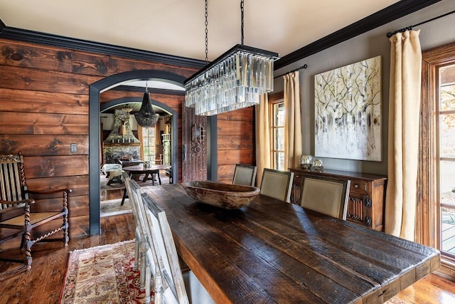 unfurnished dining area with a chandelier, hardwood / wood-style flooring, crown molding, and plenty of natural light
