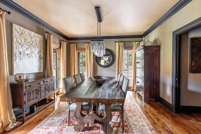 dining space featuring ornamental molding, an inviting chandelier, wood finished floors, and baseboards