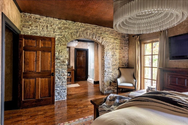 bedroom featuring arched walkways and wood finished floors