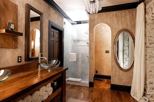 full bathroom featuring double vanity, wood finished floors, a stall shower, and a sink