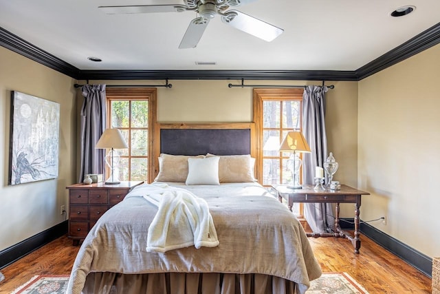bedroom with crown molding, visible vents, baseboards, wood finished floors, and a ceiling fan
