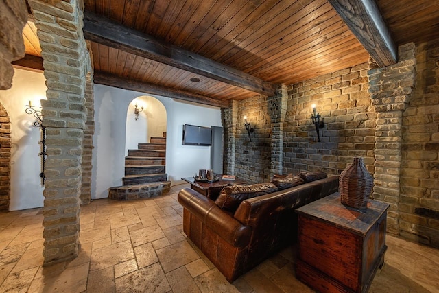 home theater room with beamed ceiling, stone tile floors, arched walkways, and wooden ceiling