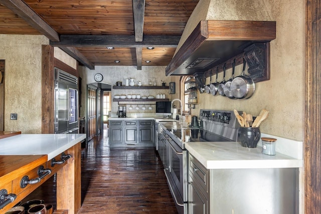 kitchen featuring light countertops, beam ceiling, appliances with stainless steel finishes, and dark wood-type flooring