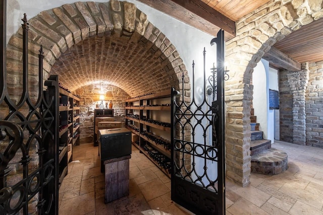 wine room featuring vaulted ceiling, stone tile flooring, and wood ceiling