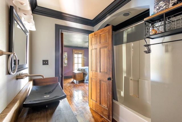bathroom with ornamental molding, hardwood / wood-style flooring, and  shower combination