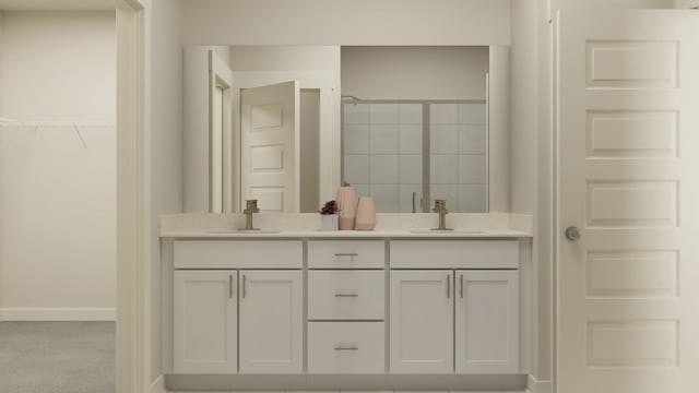 bathroom with a walk in closet, double vanity, a sink, and a shower stall