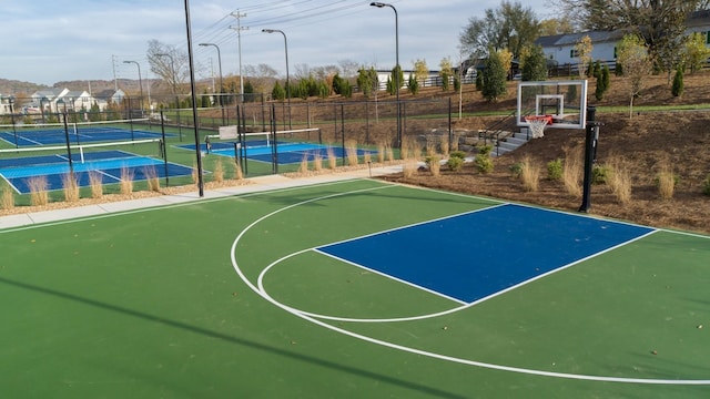 view of sport court with a tennis court, fence, community basketball court, and a residential view