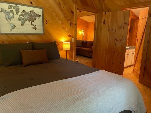 bedroom with light wood-type flooring and wooden walls