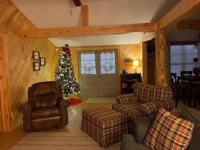 living room with beam ceiling and wood walls