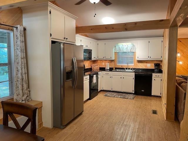 kitchen featuring light wood-type flooring, black appliances, dark countertops, and plenty of natural light