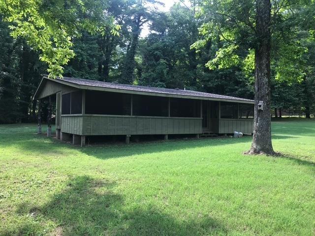 back of house featuring a lawn, a sunroom, and a forest view
