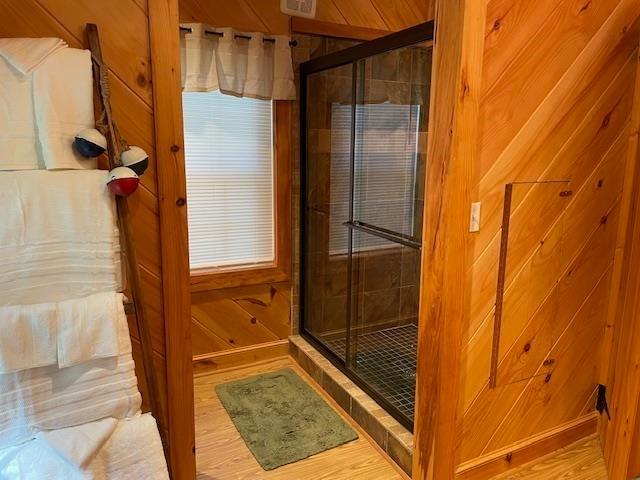 bathroom featuring a stall shower, wooden walls, and wood finished floors