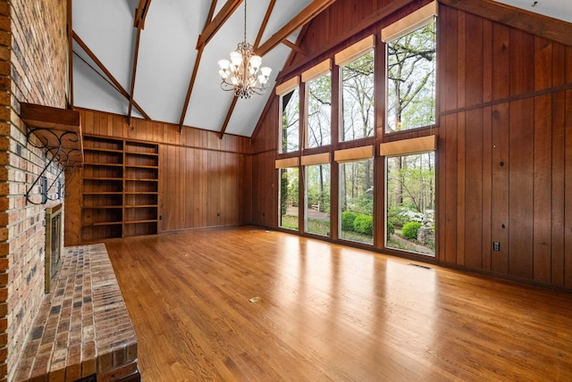 1331 Hutcheson Ln, Clarksville, TN 37040 - unfurnished living room featuring an inviting chandelier, high vaulted ceiling, wooden walls, visible vents, and wood finished floors