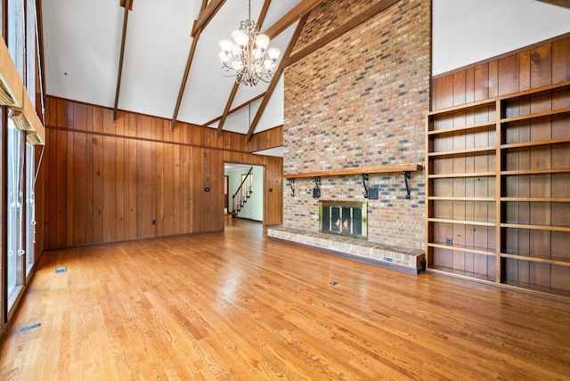 1331 Hutcheson Ln, Clarksville, TN 37040 - unfurnished living room featuring a chandelier, beam ceiling, wooden walls, high vaulted ceiling, and stairs