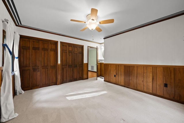 1331 Hutcheson Ln, Clarksville, TN 37040 - unfurnished bedroom with carpet floors, crown molding, wooden walls, a ceiling fan, and multiple closets