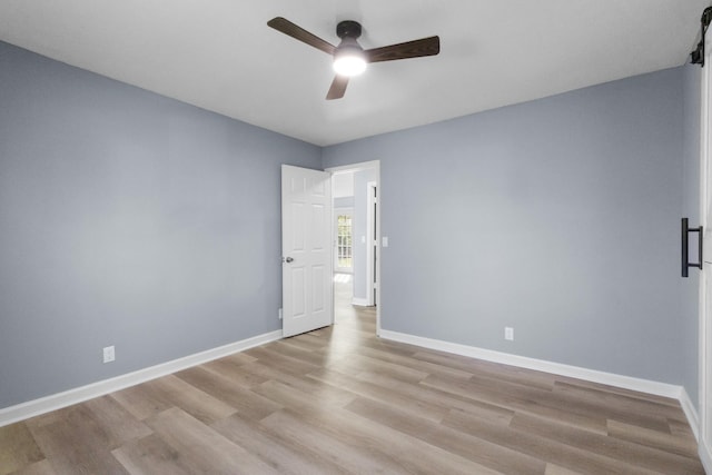 spare room featuring baseboards, wood finished floors, and a ceiling fan
