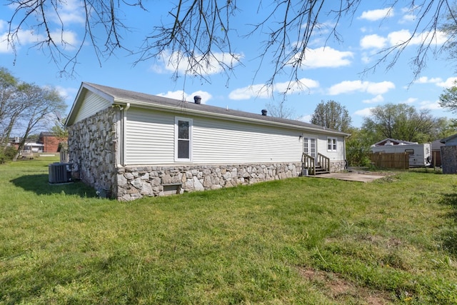 view of side of home featuring a lawn, a patio, entry steps, and stone siding