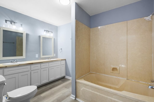 bathroom featuring double vanity, wood finished floors, toilet, and a sink