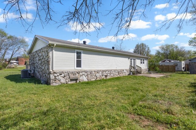 view of side of home featuring a lawn, a patio, entry steps, and stone siding