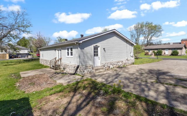 rear view of house with entry steps and a yard