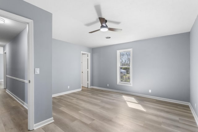 empty room featuring ceiling fan, wood finished floors, and baseboards