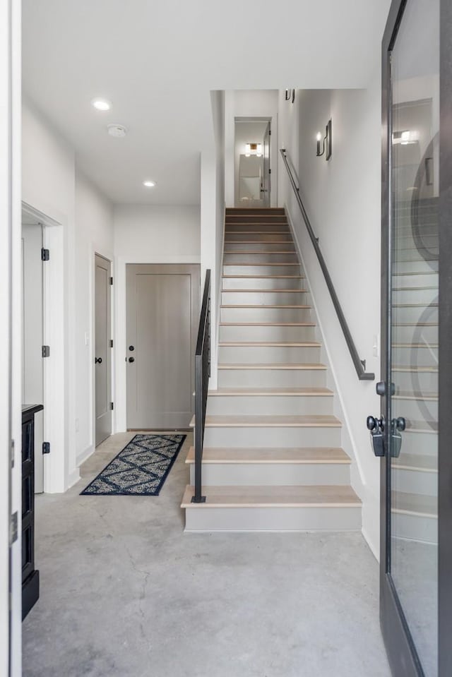 stairs featuring recessed lighting and concrete floors