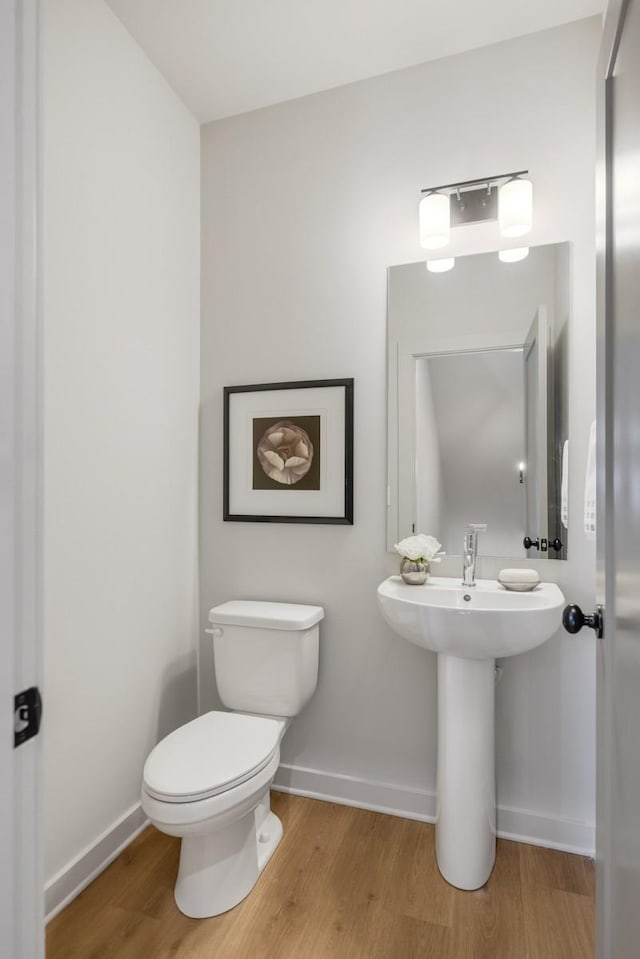 bathroom with toilet, wood finished floors, and baseboards