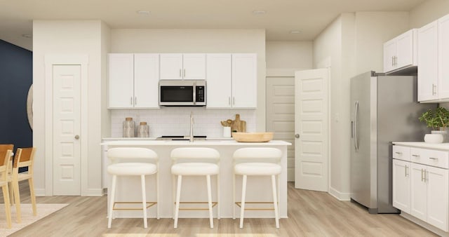 kitchen with appliances with stainless steel finishes, white cabinetry, light wood-type flooring, and backsplash