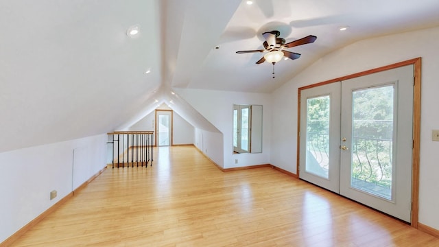 additional living space with lofted ceiling, light wood-type flooring, a ceiling fan, baseboards, and french doors