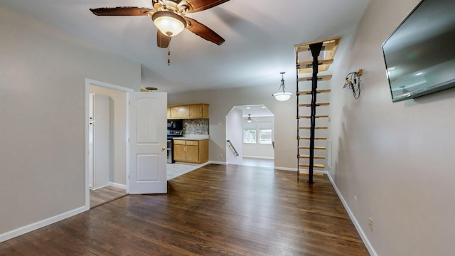 unfurnished living room featuring a ceiling fan, wood finished floors, and baseboards