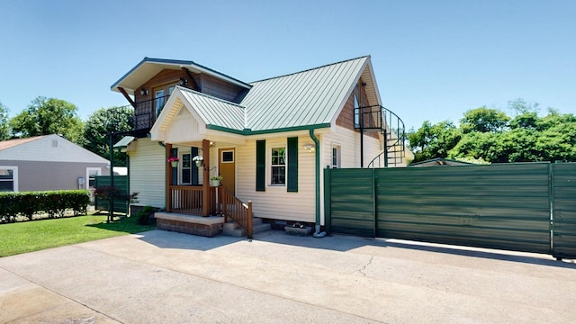 view of front of property with fence, metal roof, and a balcony