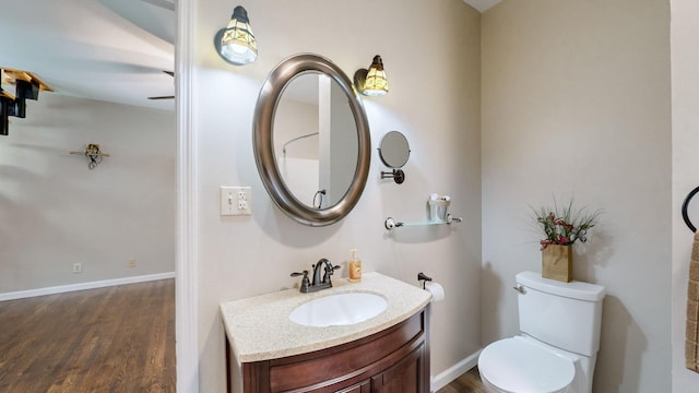 bathroom featuring wood finished floors, toilet, vanity, and baseboards