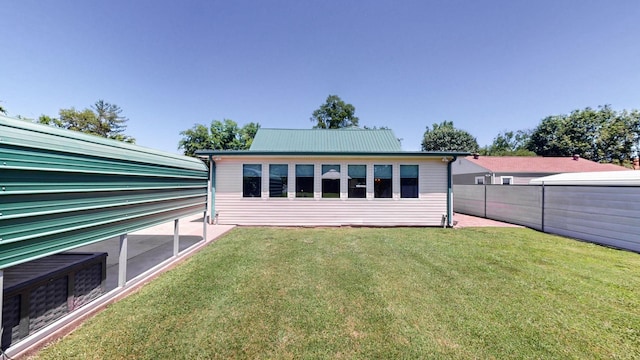 rear view of property with fence, a yard, a patio area, and metal roof