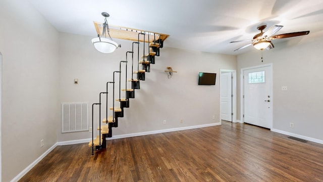 unfurnished living room featuring ceiling fan, stairs, visible vents, baseboards, and wood finished floors