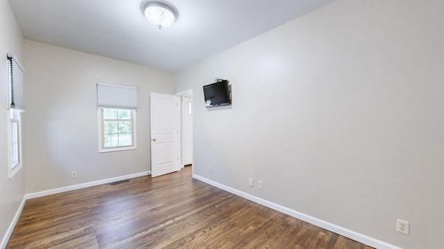 unfurnished room with visible vents, wood finished floors, and baseboards