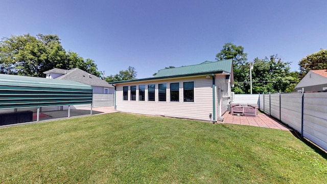 rear view of house featuring metal roof, a lawn, a patio, and a fenced backyard
