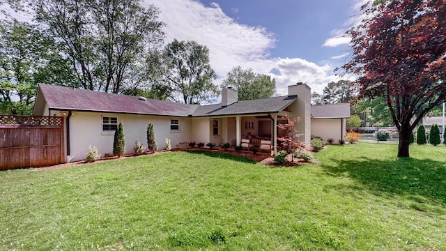rear view of house with fence, a chimney, a yard, and brick siding