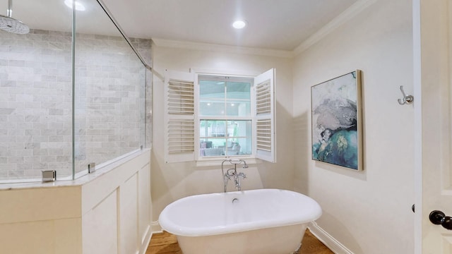 bathroom with baseboards, a walk in shower, a freestanding bath, and ornamental molding