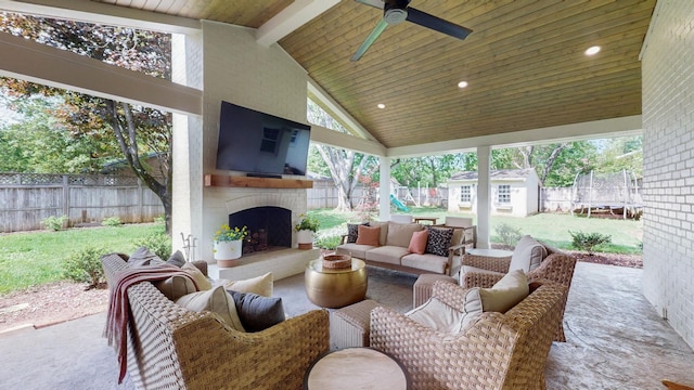 view of patio / terrace with a trampoline, an outdoor structure, an outdoor living space with a fireplace, a fenced backyard, and a storage shed