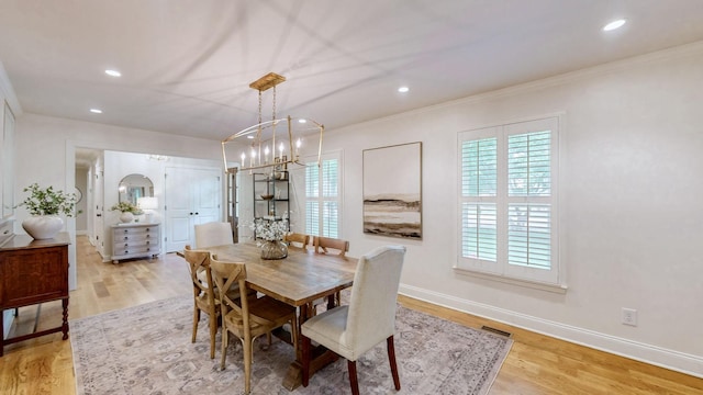 dining room with crown molding, baseboards, and light wood-style floors